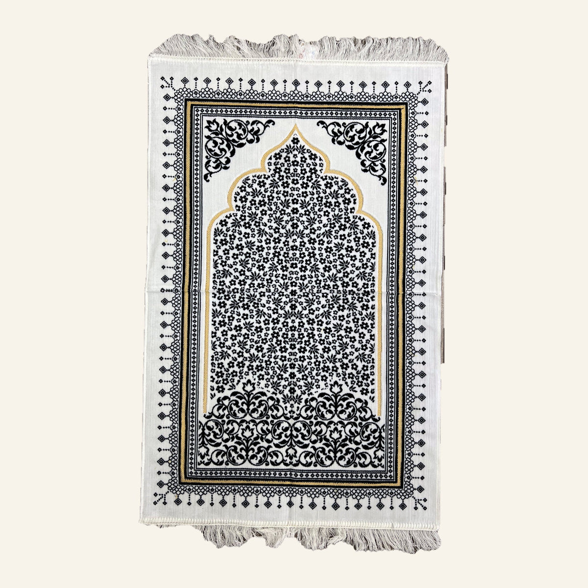 Turkish prayer mat in dark blue on a cream ground, laid flat — gold-outlined mihrab arch filled with small flowers, scrolled corner medallions, diamond border, knotted fringe at both ends.