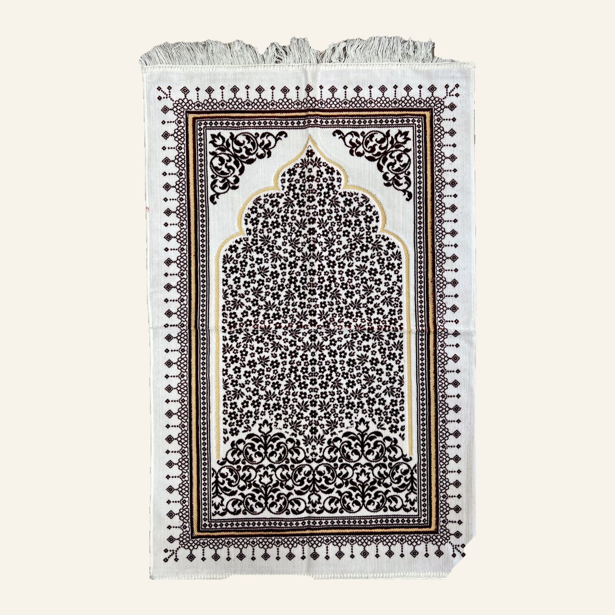 Turkish prayer mat in dark red on a cream ground, laid flat — gold-outlined mihrab arch filled with small flowers, scrolled corner medallions, diamond border, knotted fringe at both ends.